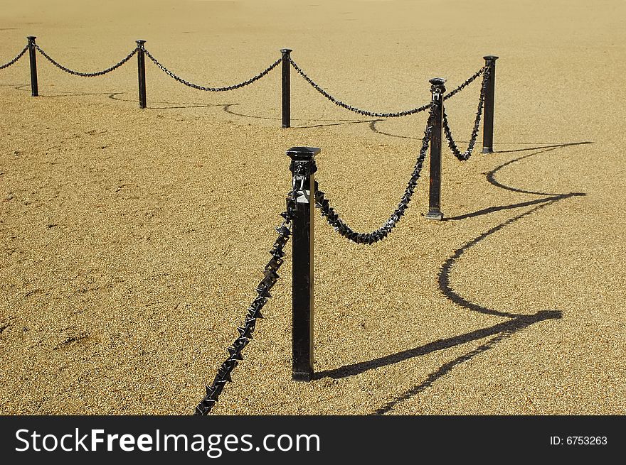 Chain link fencing with looping shadows on a gravel background. Chain link fencing with looping shadows on a gravel background