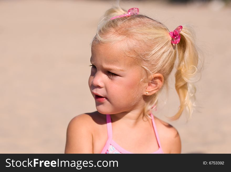 Little girl sitting in the sand at the beach. Little girl sitting in the sand at the beach