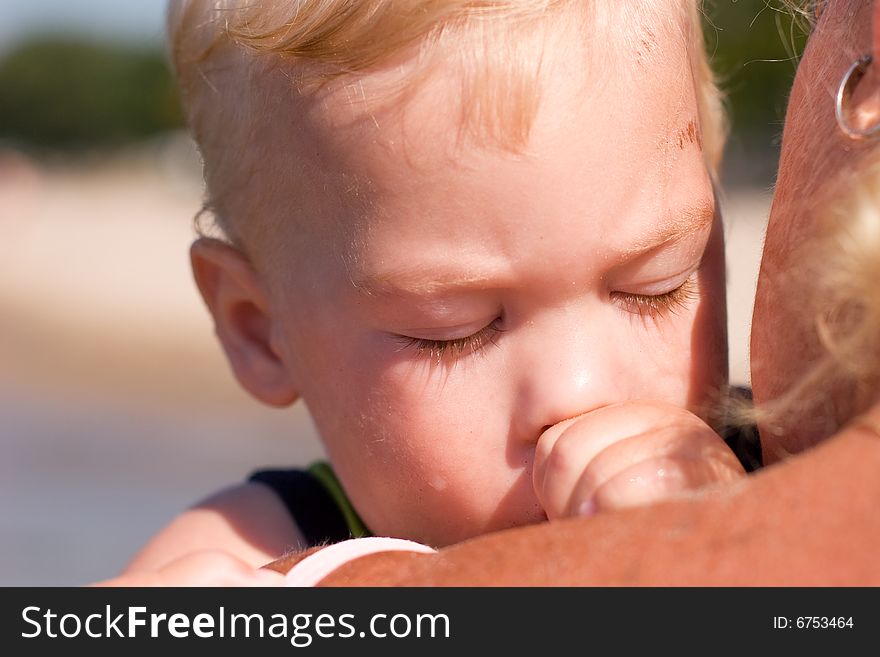 Young boy sleeping in his mother's arms. Young boy sleeping in his mother's arms