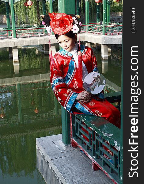 A beautiful girl in Chinese ancient dress is sitting in the ancient long corridor of China. This is dress of Qing Dynasty of China. It is the princess' dress too. Chinese on the fan is meant and missed. A beautiful girl in Chinese ancient dress is sitting in the ancient long corridor of China. This is dress of Qing Dynasty of China. It is the princess' dress too. Chinese on the fan is meant and missed.