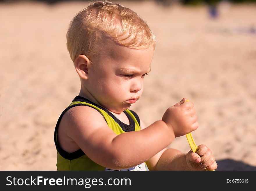 Young boy playing with a bucket at the beach. Young boy playing with a bucket at the beach