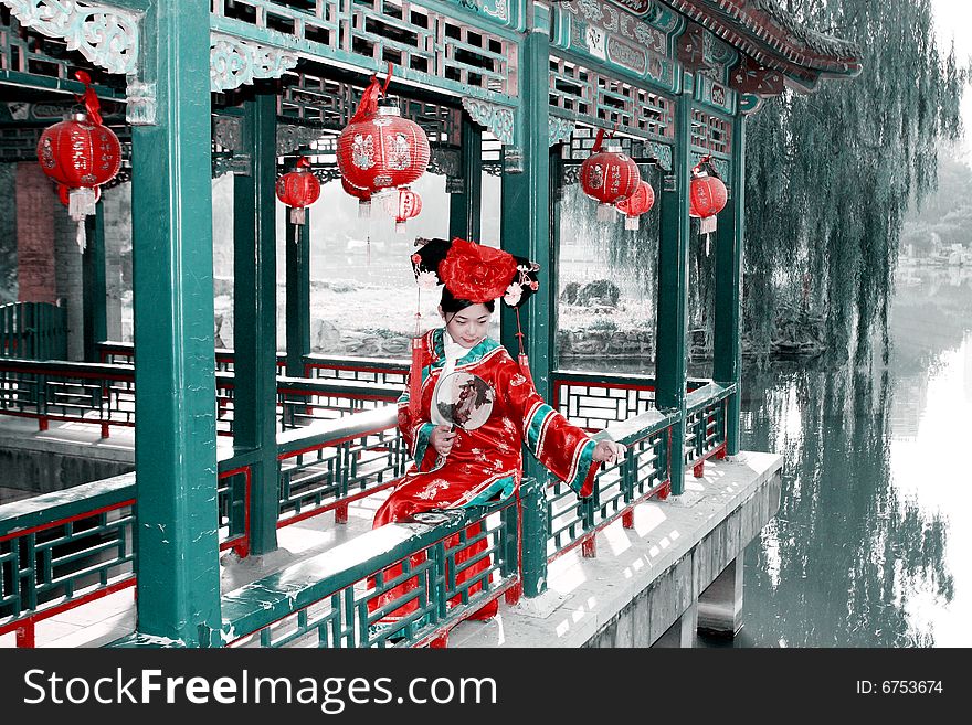 A beautiful girl in Chinese ancient dress is sitting in the ancient long corridor of China. She is feeding the goldfish in water. Chinese on the fan is meant and missed. Chinese on the lantern is lucky and getting rich. A beautiful girl in Chinese ancient dress is sitting in the ancient long corridor of China. She is feeding the goldfish in water. Chinese on the fan is meant and missed. Chinese on the lantern is lucky and getting rich.