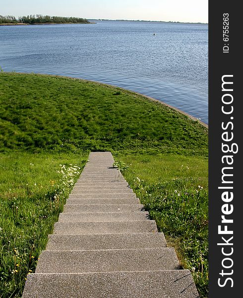 Stairway in the grassy hillside runs to nowhere on the shore of the lake. Stairway in the grassy hillside runs to nowhere on the shore of the lake