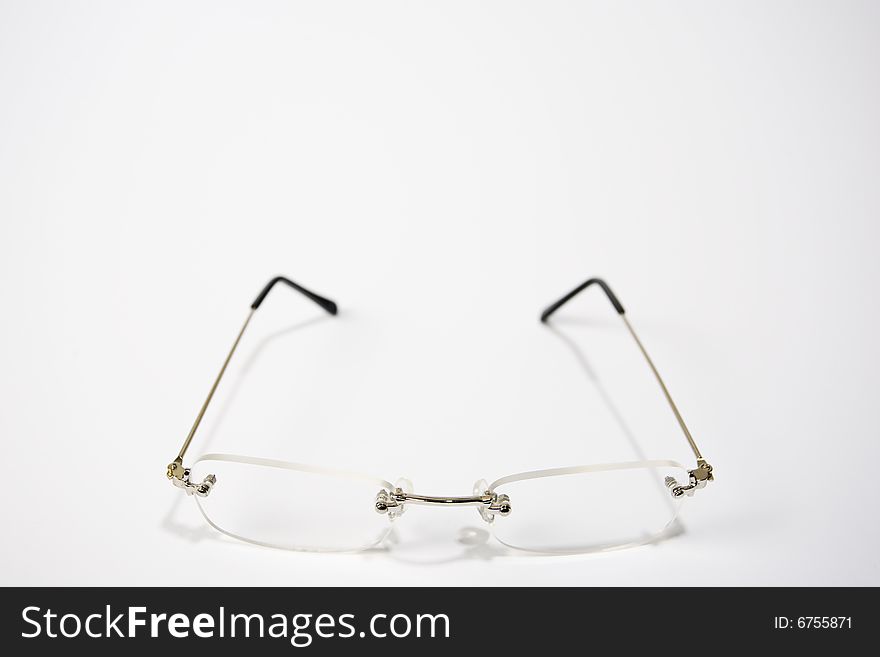 A pair of reading glasses facing front and center of a white frame