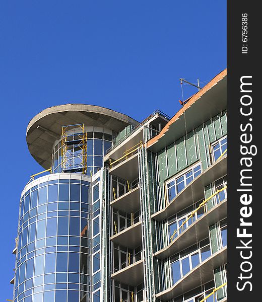 The Construction of the building. The Sun sparkles in new glass, on background blue sky.