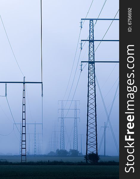 A power transmission line in morning fog.