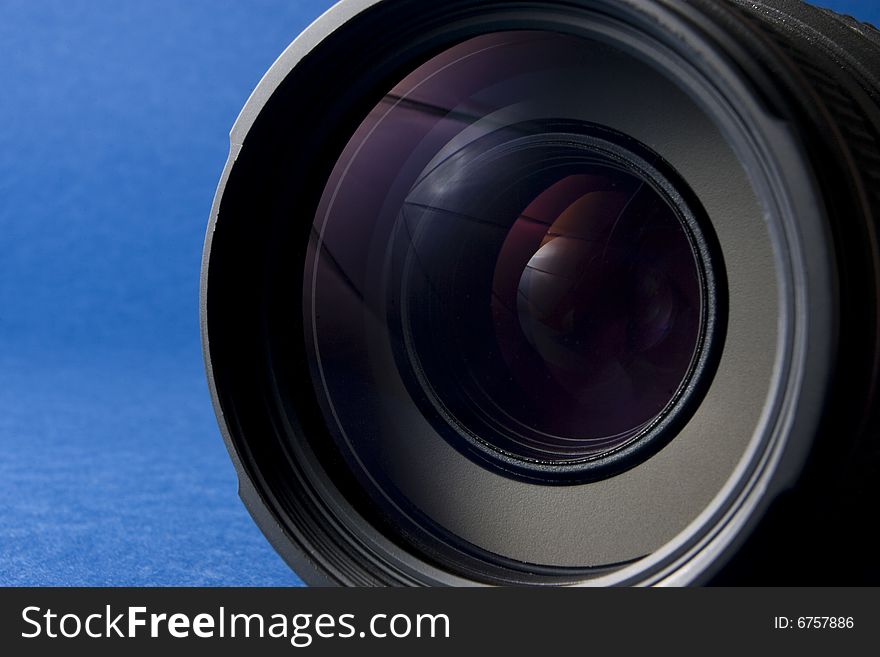 Front elements of a lens on the right-hand side of a blue background providing copy space. Front elements of a lens on the right-hand side of a blue background providing copy space