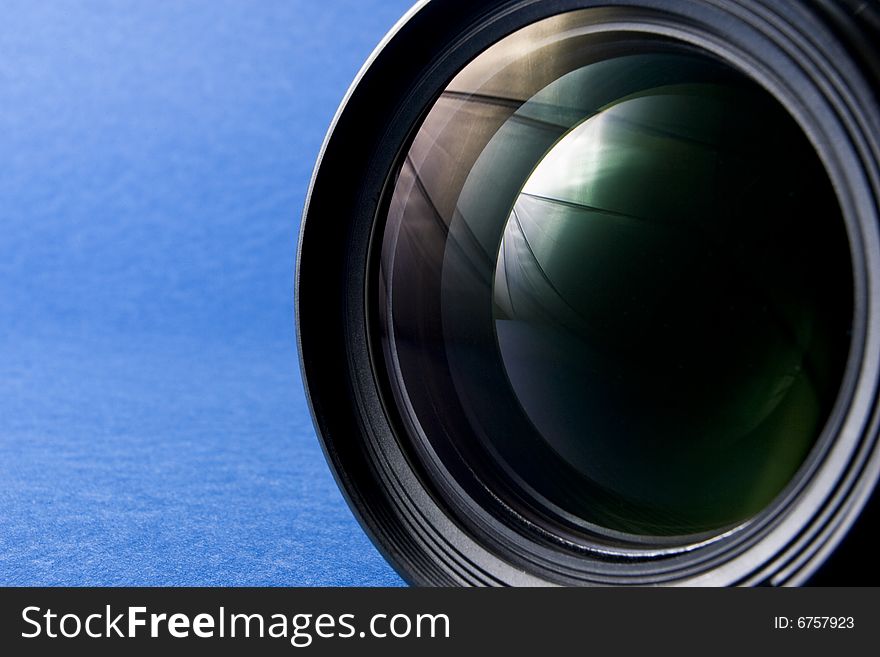 Front elements of a lens on the right-hand side of a blue background providing copy space. Front elements of a lens on the right-hand side of a blue background providing copy space