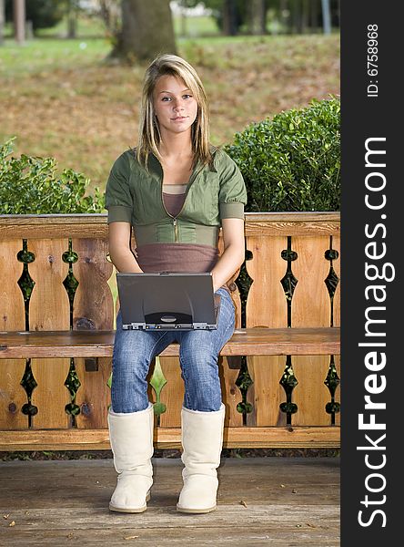 A beautiful blond teenage girl using her laptop in the park