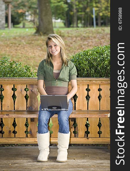 A beautiful blond teenage girl using her laptop in the park