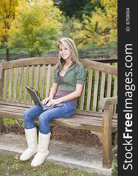 A beautiful blond teenage girl using her laptop in the park