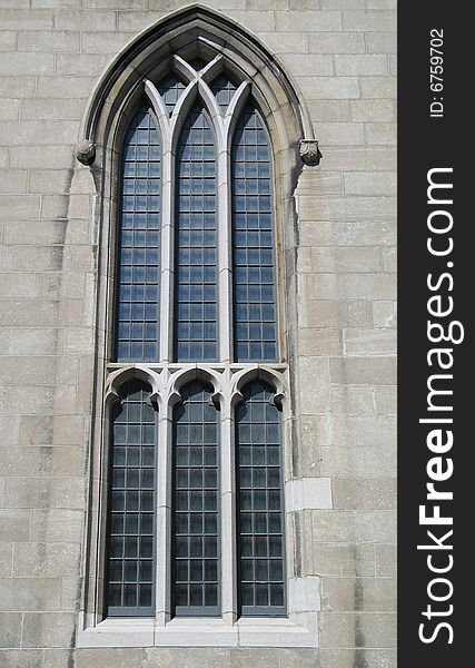 an old church window and grey block wall