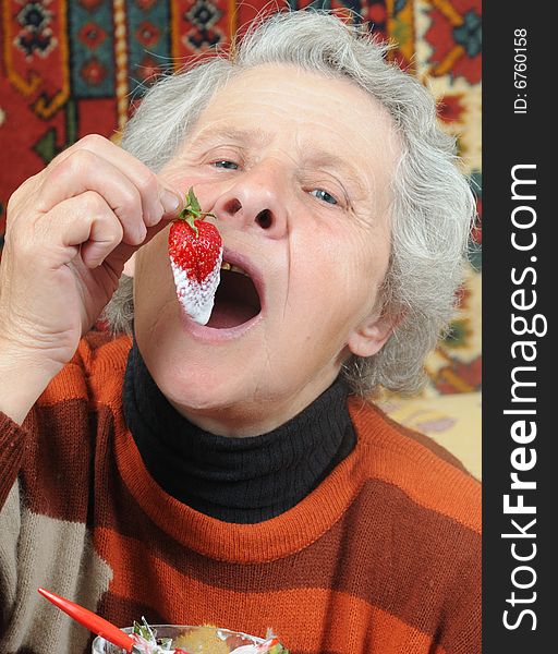 Grandmother eats a ripe strawberry. Grandmother eats a ripe strawberry