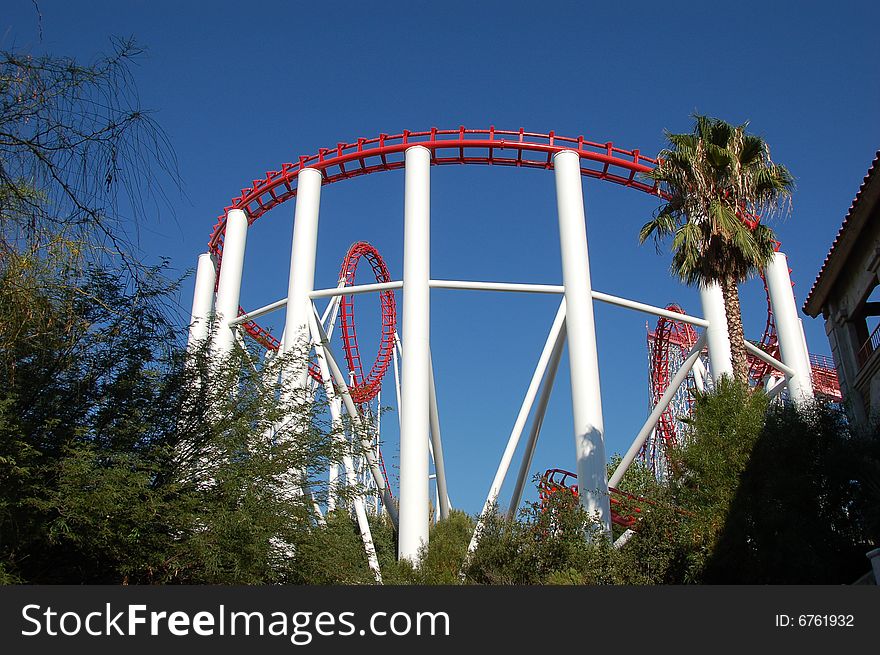 Red and white Rollercoaster against blue sky