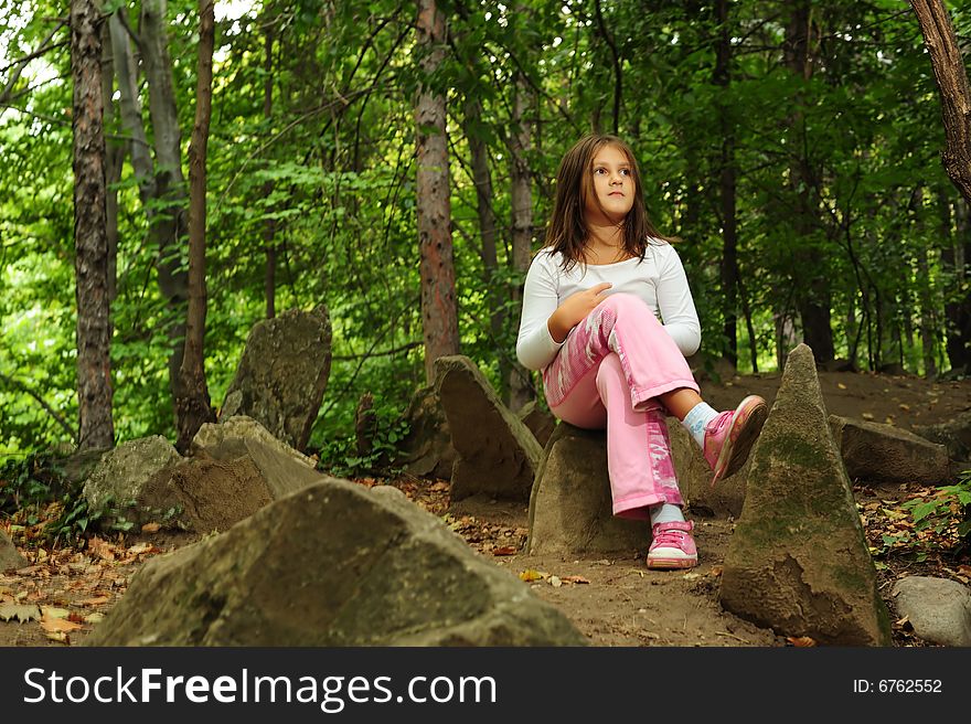 A little girl standing on a rock in forest. A little girl standing on a rock in forest