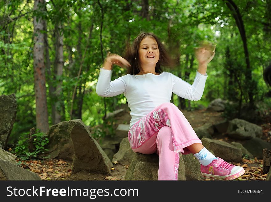 A little girl standing on a rock in forest, motion blur effect. A little girl standing on a rock in forest, motion blur effect