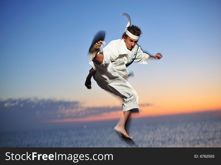 Young boy in karate uniform training at sunset. Young boy in karate uniform training at sunset