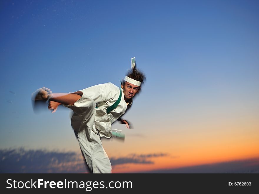 Young boy in karate uniform training at sunset