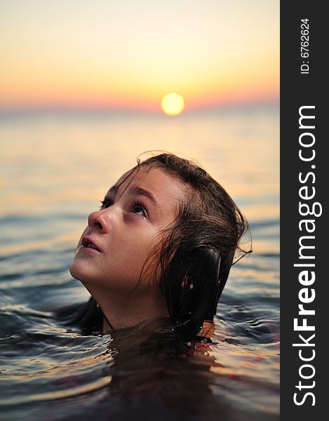 Young girl in red dress standing in sea at sunset. Young girl in red dress standing in sea at sunset