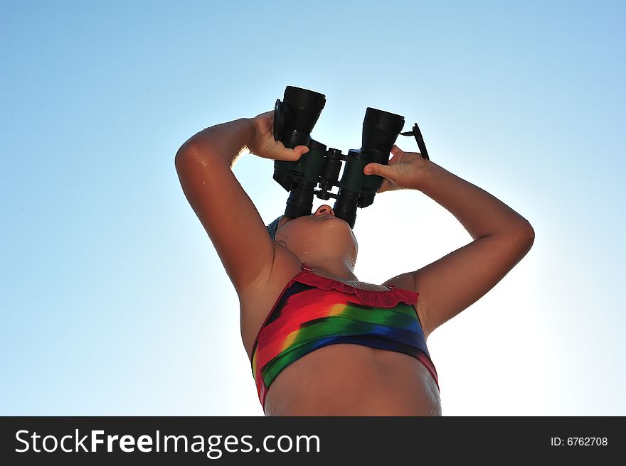 Young girl looking through binocular, low angle view. Young girl looking through binocular, low angle view