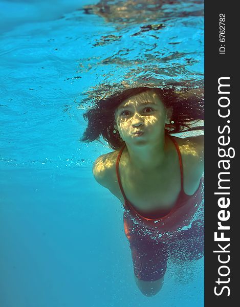 Little girl swimming underwater in pool