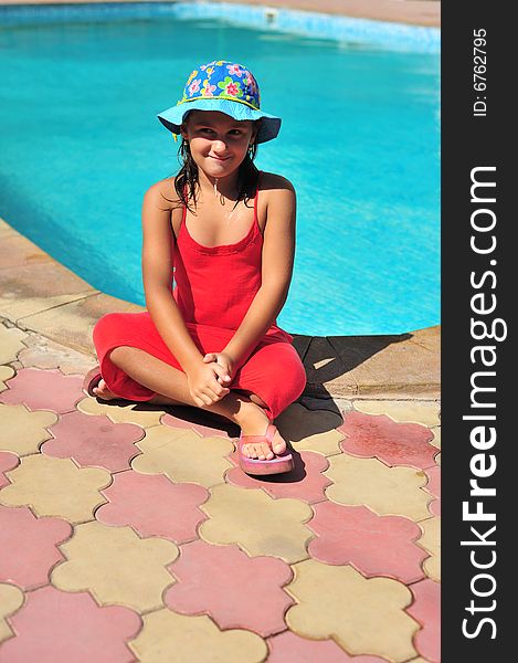 Young girl in red dress standing near pool. Young girl in red dress standing near pool