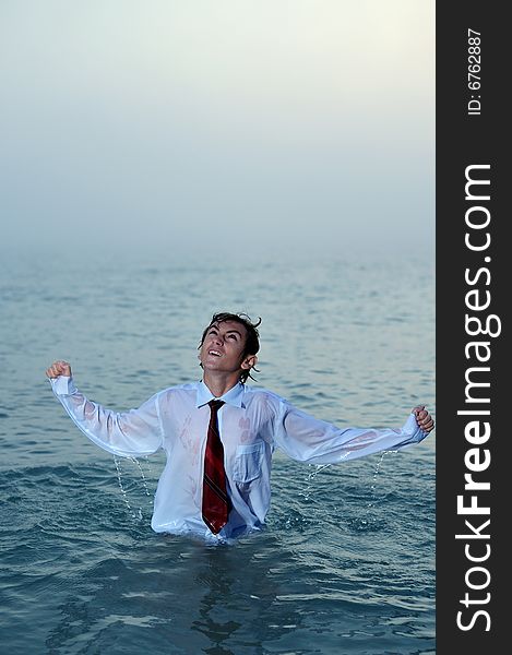 Young businessman standing on sea and looking up