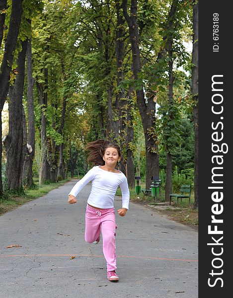 Young girl running on alley in a park