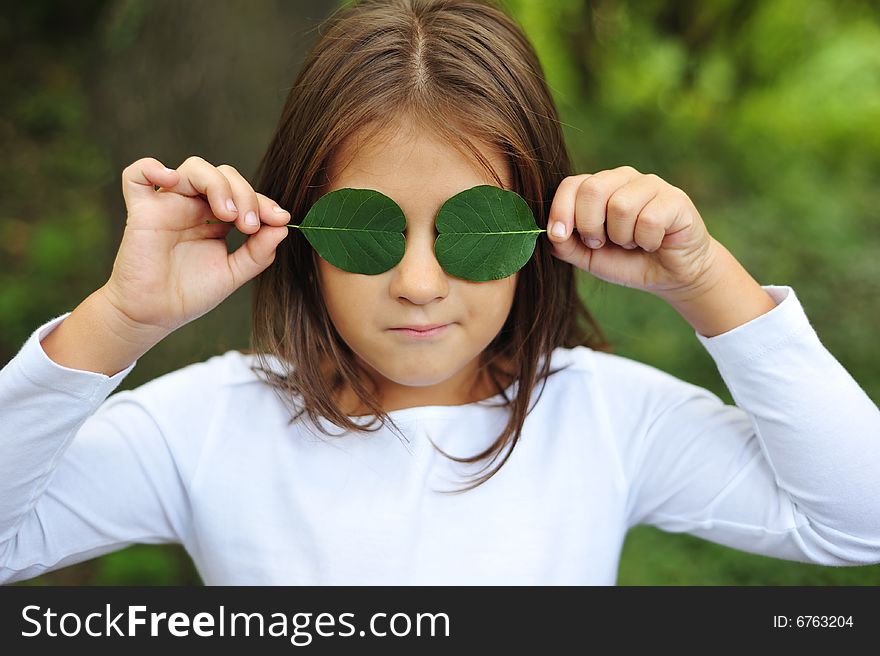 Little girl holding two leaf on eyes