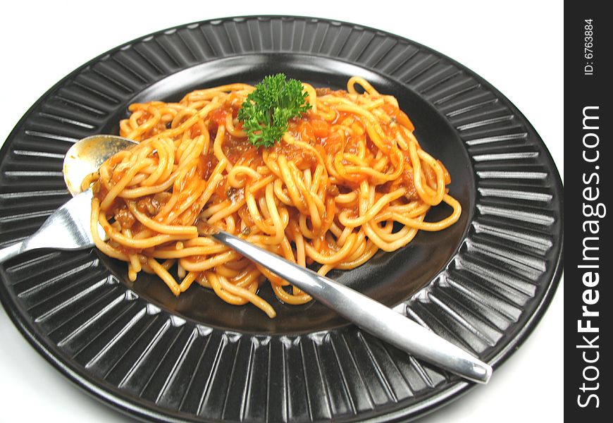 A plate of spaghetti with spoon and fork. A plate of spaghetti with spoon and fork