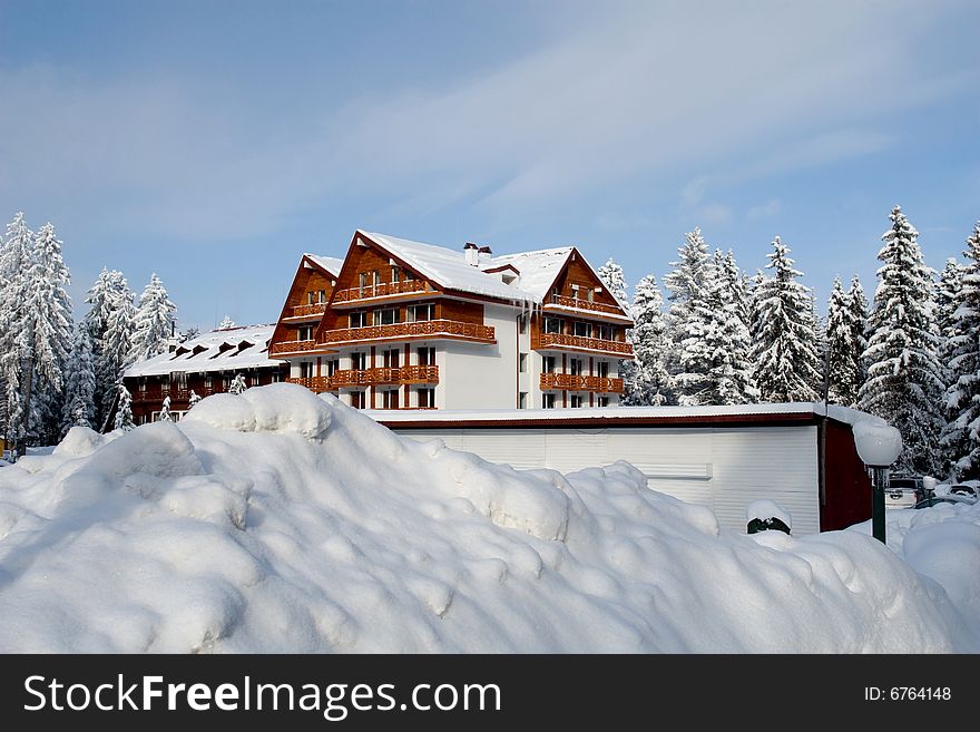 Isolate mountain cottage between evergreen trees and packs of snow. Isolate mountain cottage between evergreen trees and packs of snow