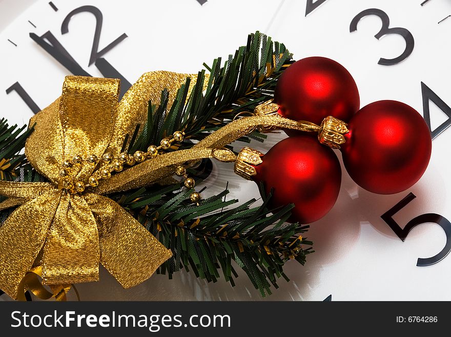 Christmas-tree decoration with red spheres on a background of clock