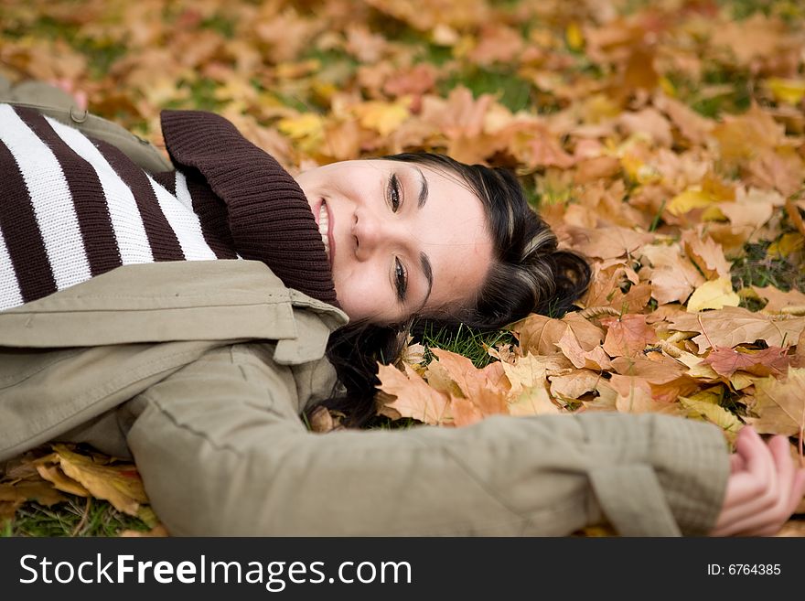 Attractive brunette woman lying on leaves. Attractive brunette woman lying on leaves