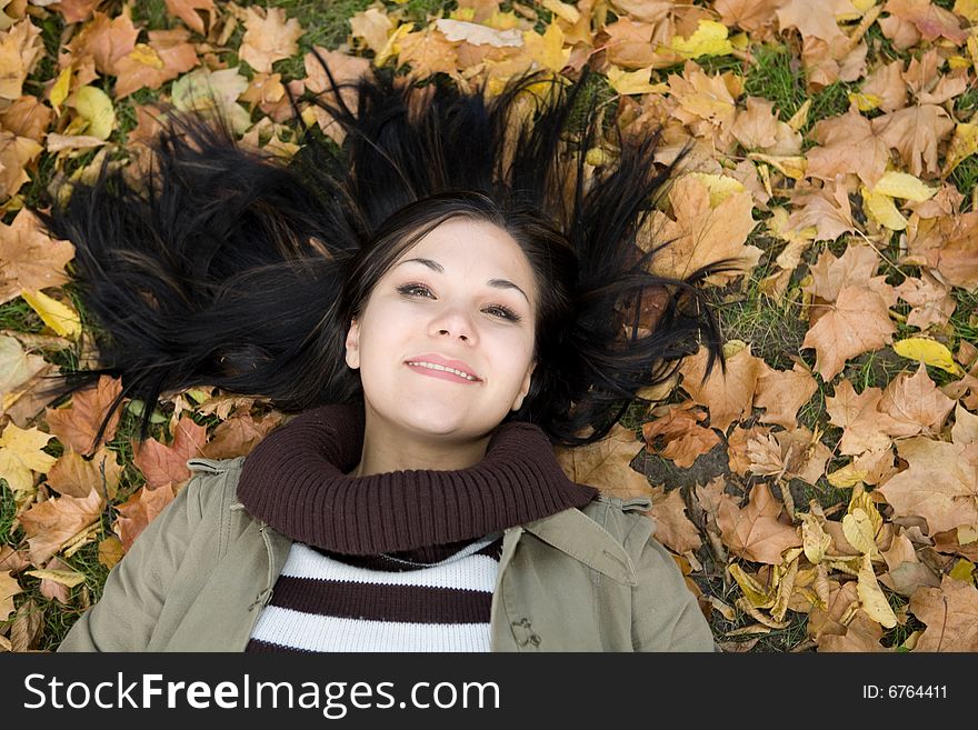 Attractive brunette woman lying on leaves. Attractive brunette woman lying on leaves