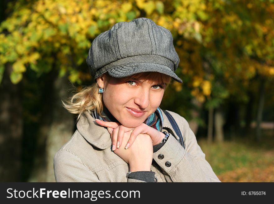 Beautiful blond young woman in cap in autumn park