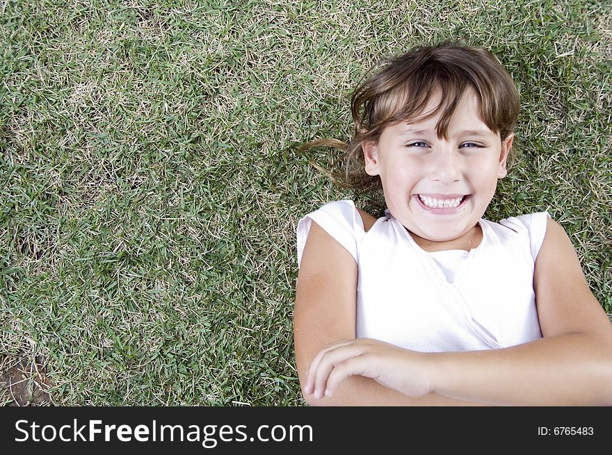 Smiling young cute girl lying on the grass