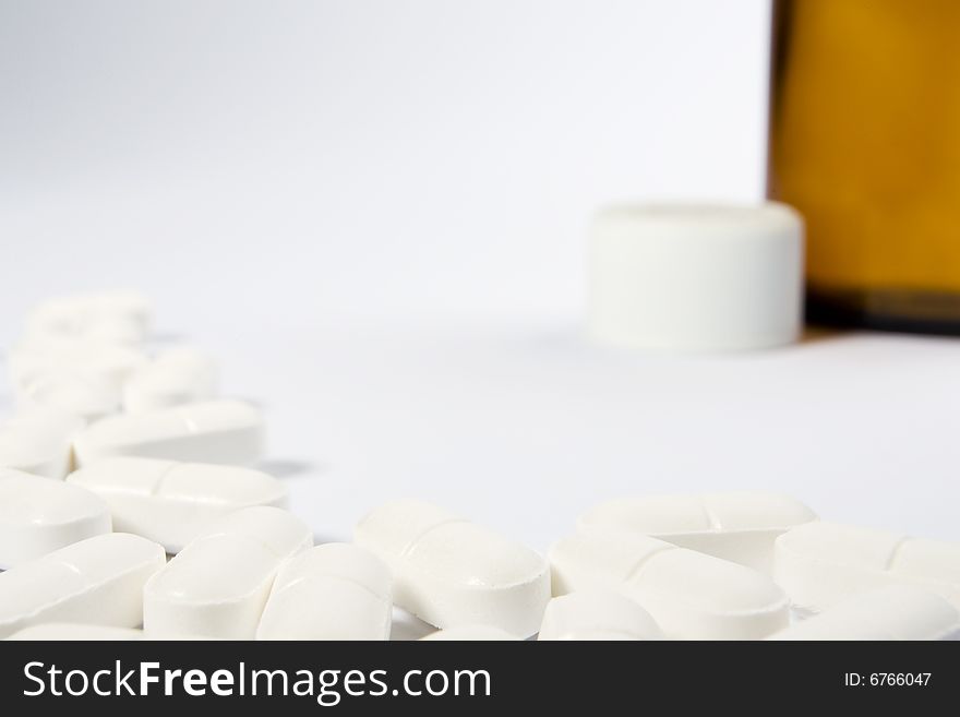 A border of pills on the left-hand side and lower part of a white frame with an opend bottle in the top right-hand area. A border of pills on the left-hand side and lower part of a white frame with an opend bottle in the top right-hand area