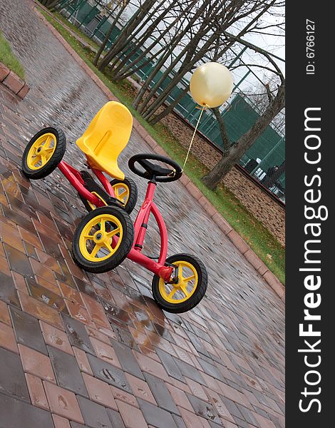 The four-wheel bicycle with yellow ball on pavement. The four-wheel bicycle with yellow ball on pavement