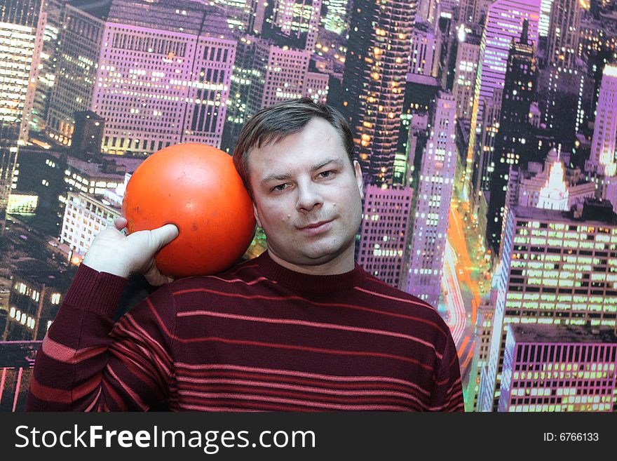 The man poses with  orange bowling ball. The man poses with  orange bowling ball