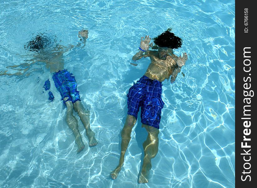 Image of boys floating underwater in pool. Image of boys floating underwater in pool