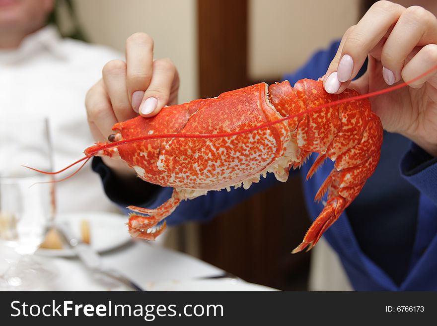 The girl holds a lobster in a restaurant