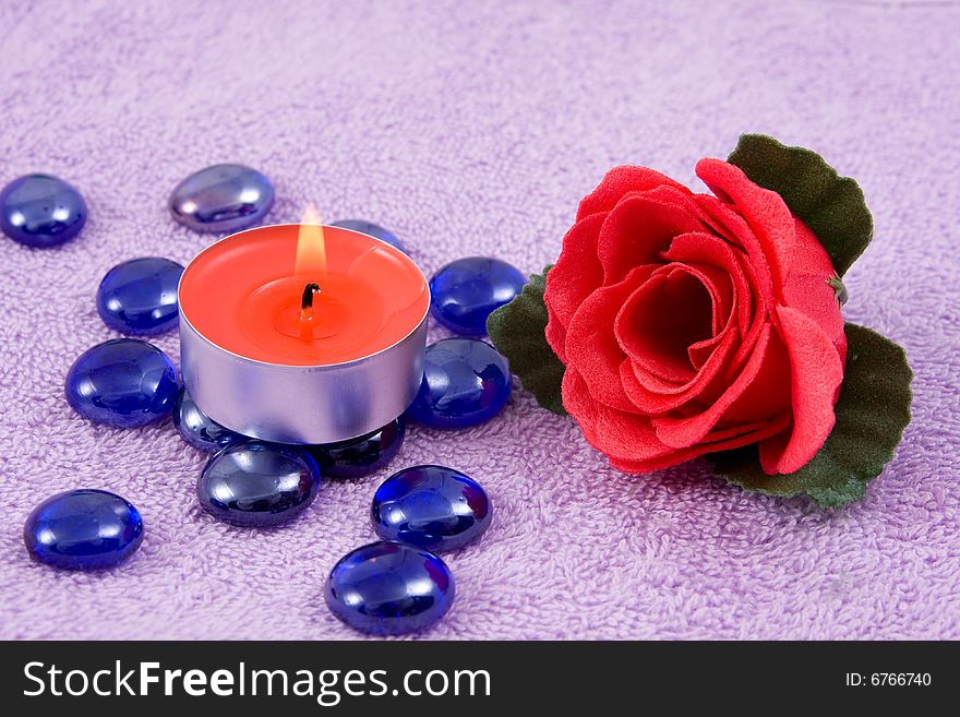 Scented  rose and  aroma candle on a background lilac towel. Scented  rose and  aroma candle on a background lilac towel