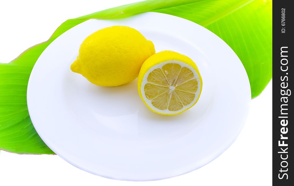 Whole and a lemon half on a white plate. Whole and a lemon half on a white plate