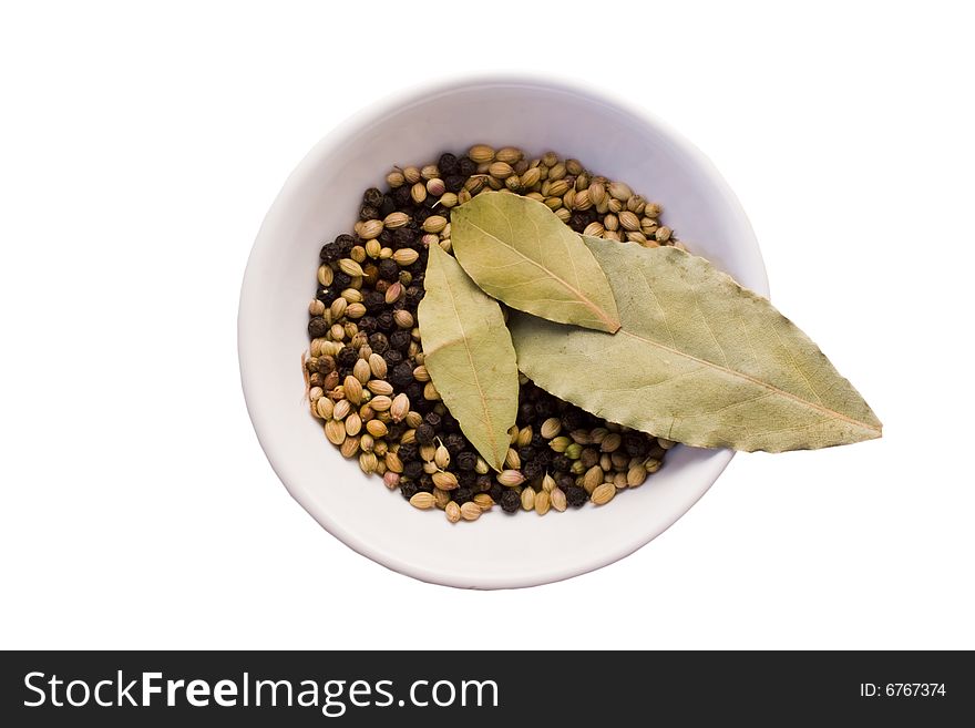 Three bay leaves,coriander seeds and black peppercorns in  porcelain bowl isolated on white background with clipping path. Three bay leaves,coriander seeds and black peppercorns in  porcelain bowl isolated on white background with clipping path