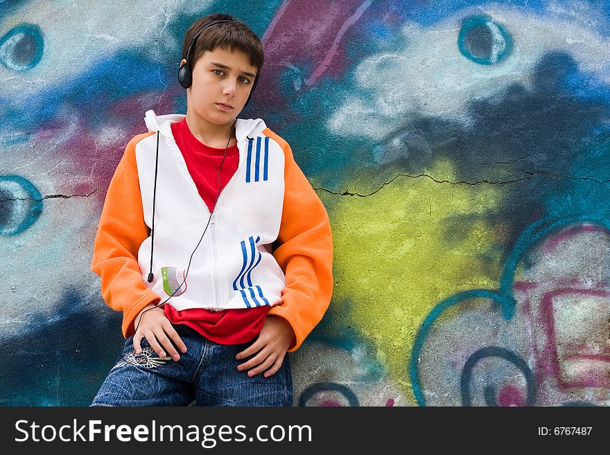 Portrait of a cool teenager listening music against a graffiti background