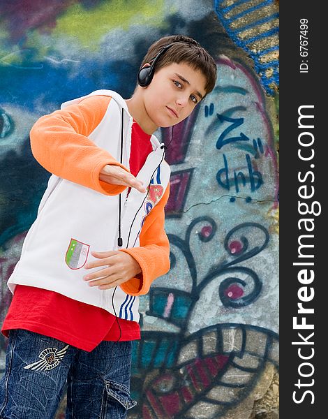 Teenager with headsets listening music against a graffiti wall. Teenager with headsets listening music against a graffiti wall