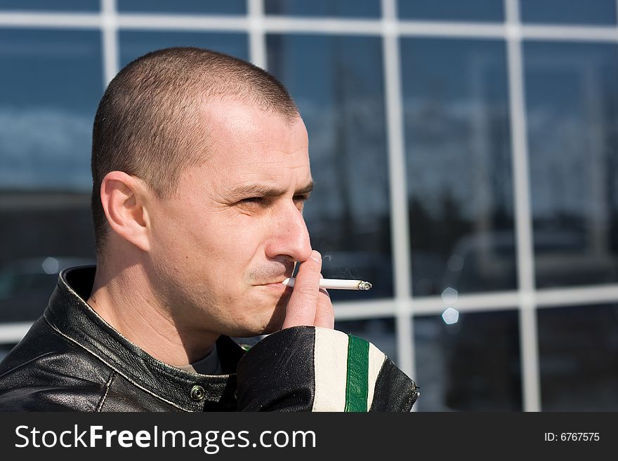 Man smoking outside on a business building background