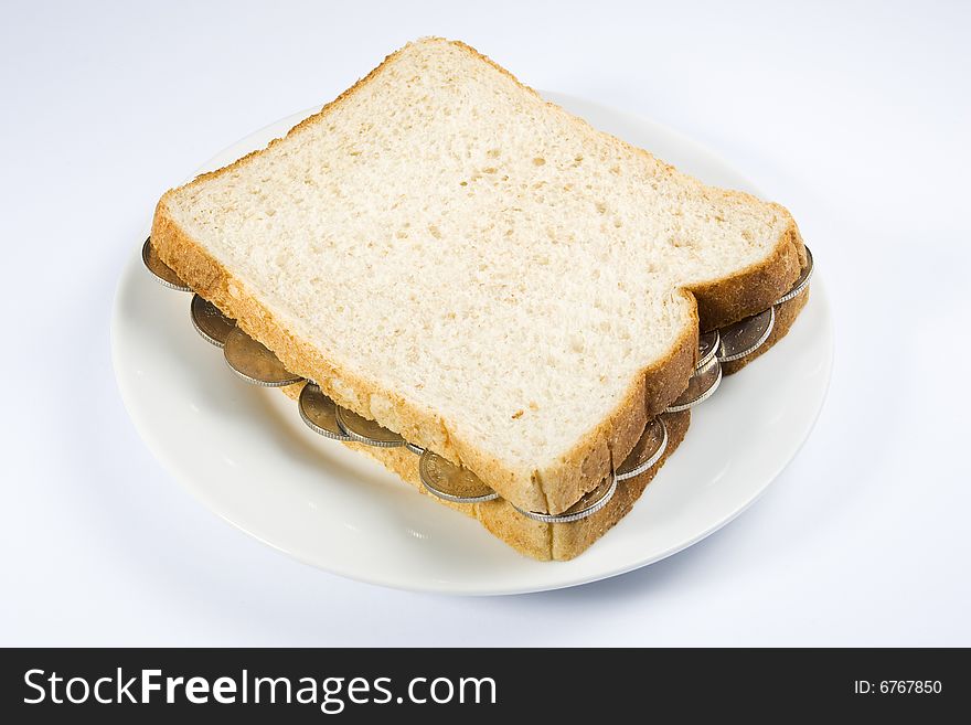 A sandwich filled with coins on a white plate. A sandwich filled with coins on a white plate