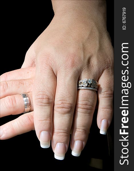 Wedding rings on bride and groom's hands on black background