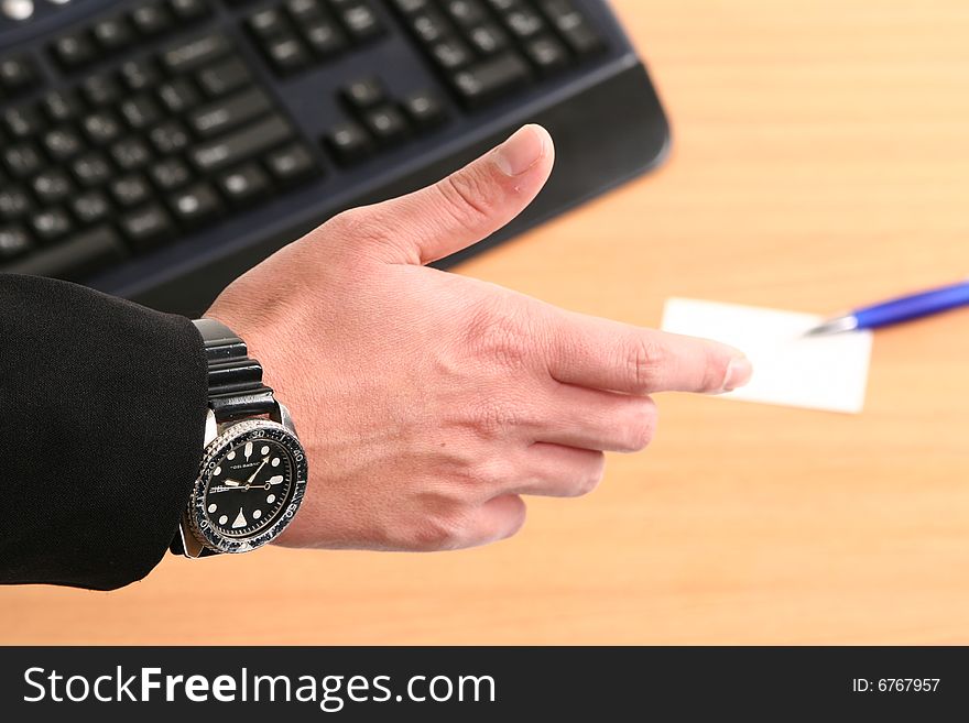 Business man reaching to shake hand with card and pen in background. Business man reaching to shake hand with card and pen in background